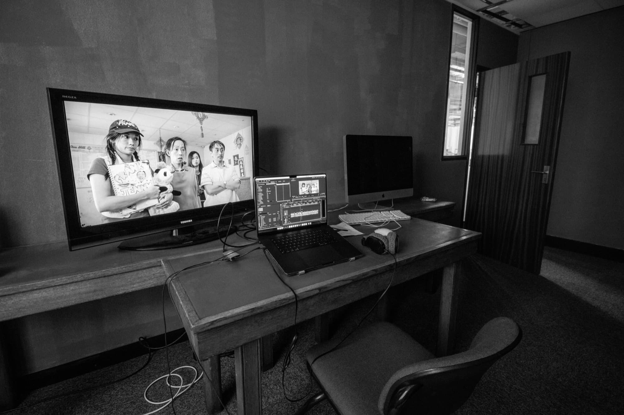 An editing suite with a monitor, laptop and headphones, showing a scene from a SNAP production