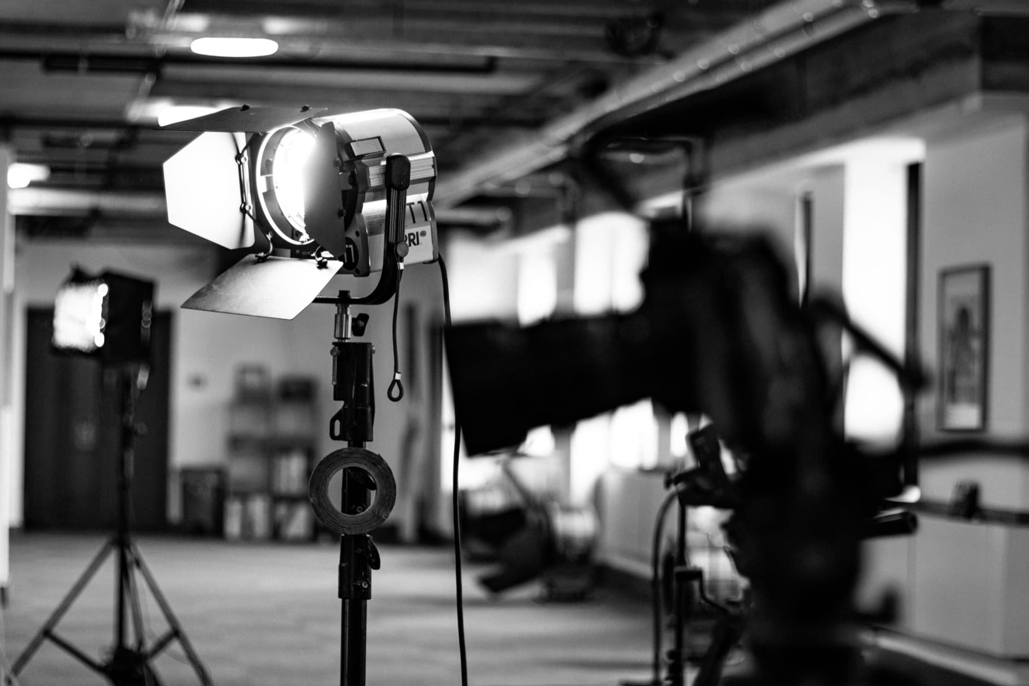 A studio light in focus with a cinema camera in the foreground